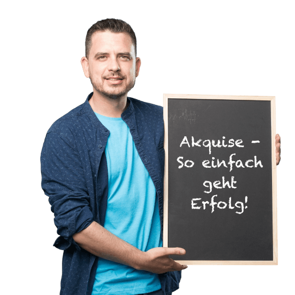 Mann hält eine Tafel mit der Aufschrift "Akquise - So einfach geht Erfolg" im Arm. Er trägt ein blaues T-Shirt und eine dunkelblaue Jacke.